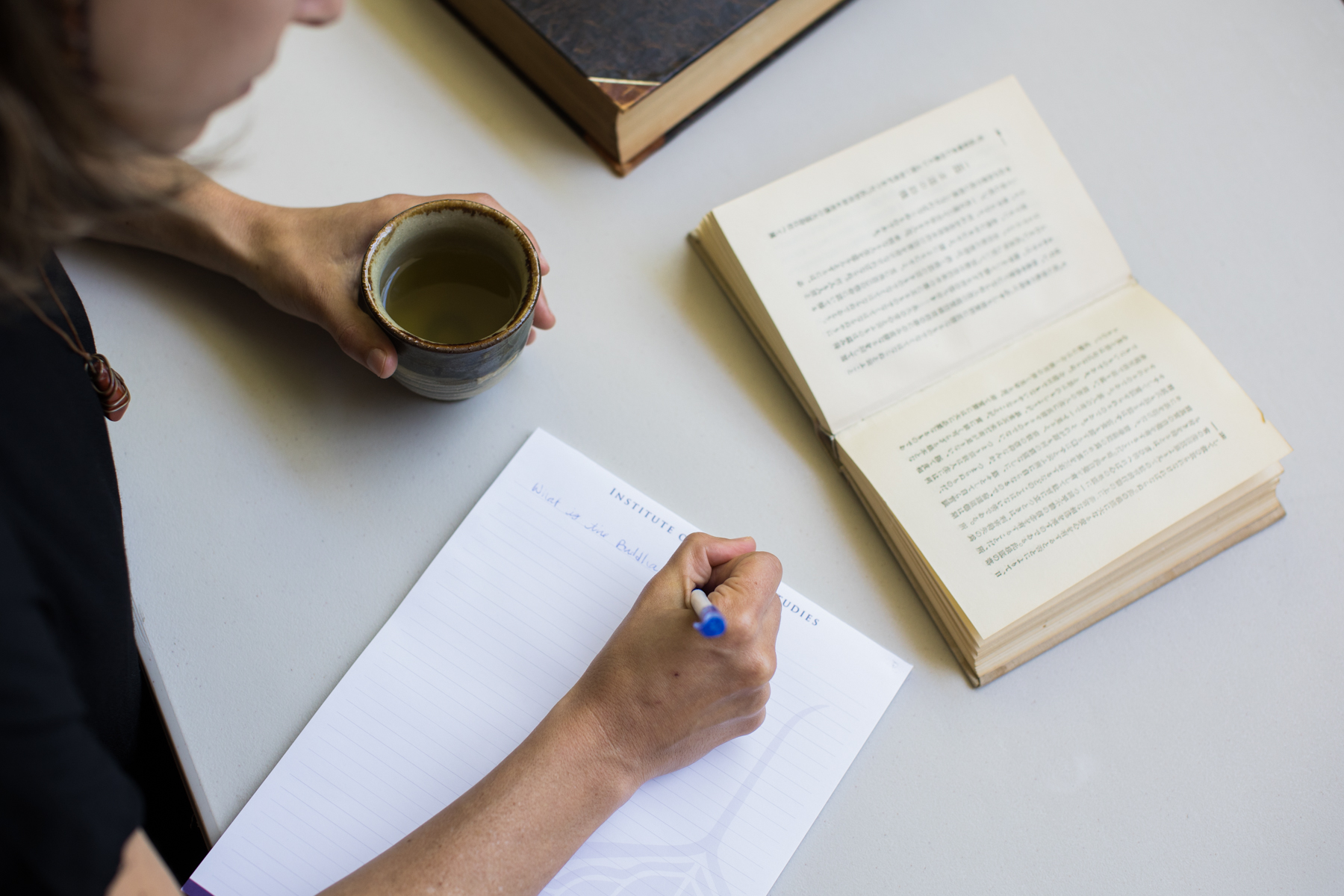 Open book on table, woman writing on paper, studying